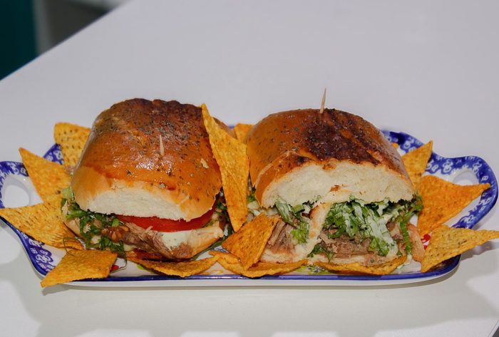 Sándwich tostado con lechuga y tomate servido con nachos