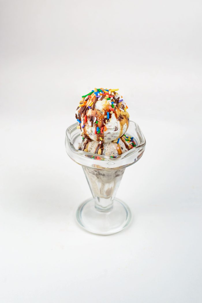 Helado con chispas de colores, nueces y salsa de chocolate en copa