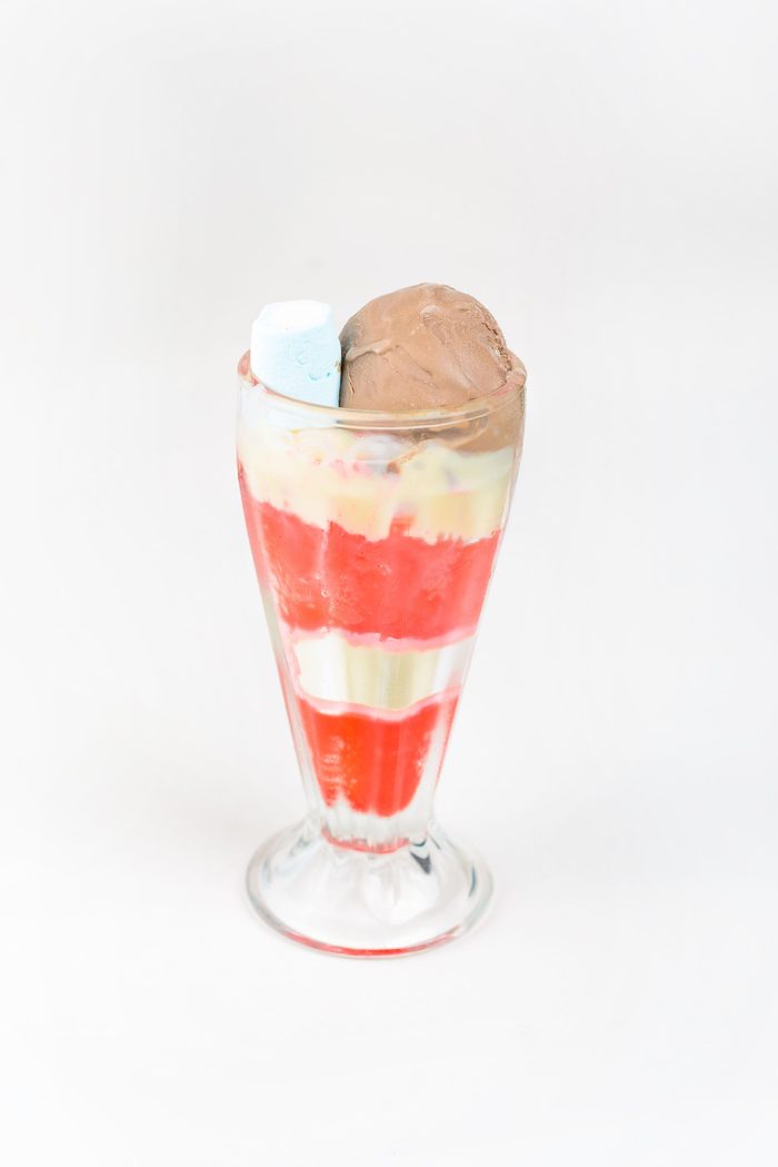 Copa alta de helado de chocolate con capas de fresa, crema y marshmallow