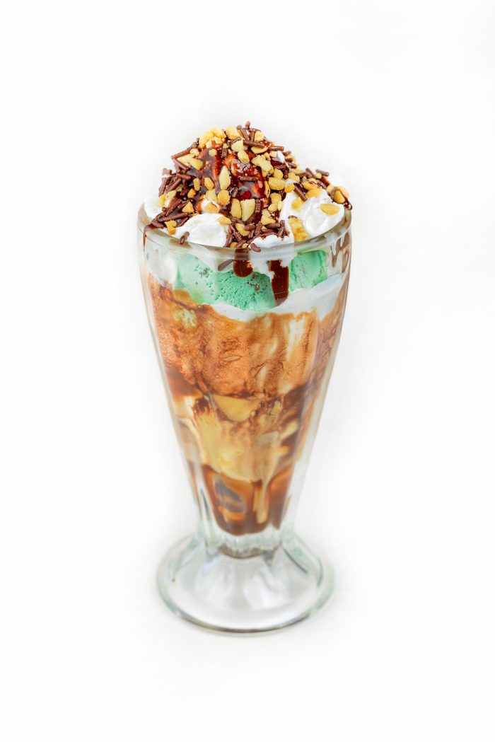 Sundae alto con helado de menta, salsa de chocolate, crema batida y maní